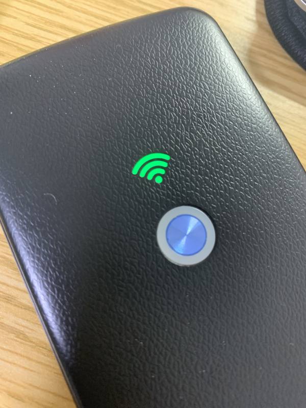 POKEFI（ポケファイ）の本体アップ写真 - 電源ボタンと緑色のWiFiインジケーターが点灯し、海外で接続成功した状態