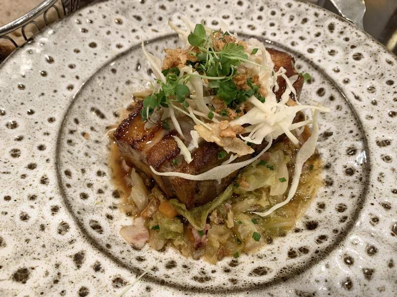 Le Comptoir du Relais(パリ6区サンジェルマン)のディナーコースで提供された豚肉のロースト料理 - キャベツとフライドオニオン、ハーブを添えた洗練された一品